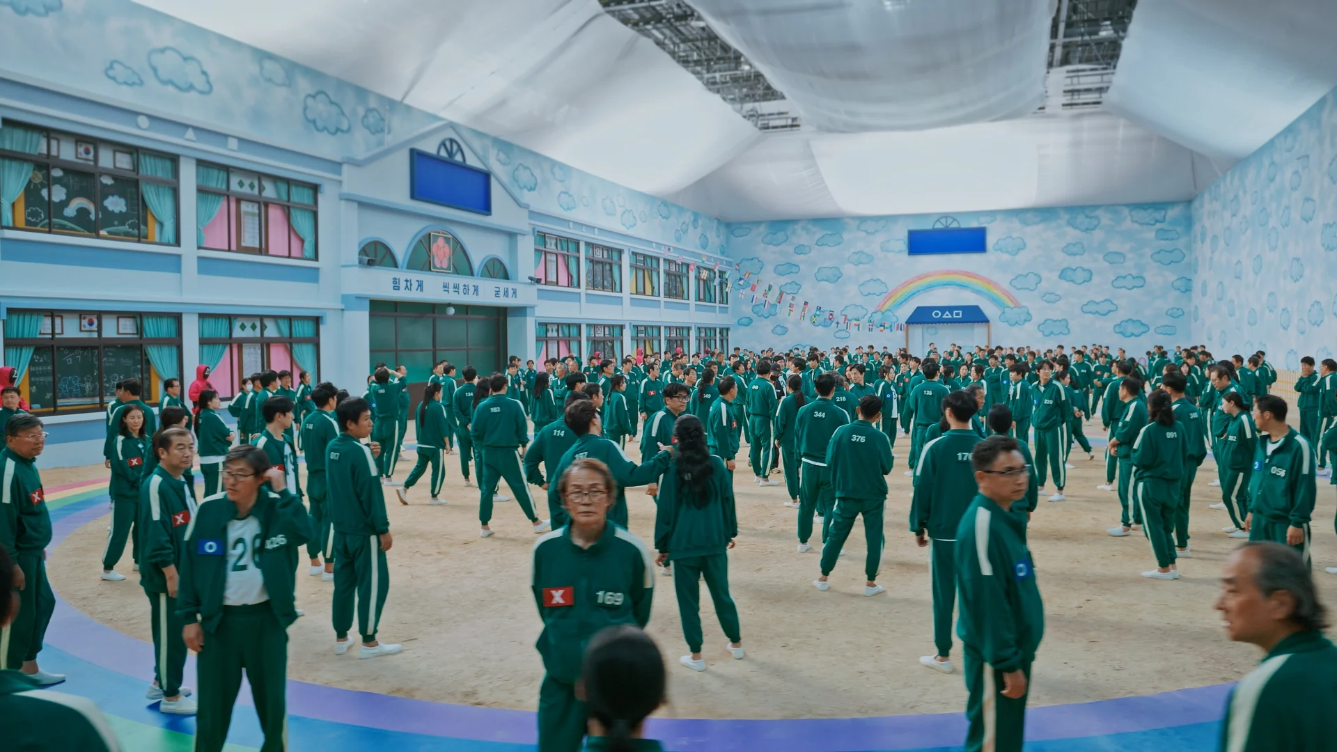 Inside Squid Game S2 — players in green tracksuits filling the dormitory hall set
