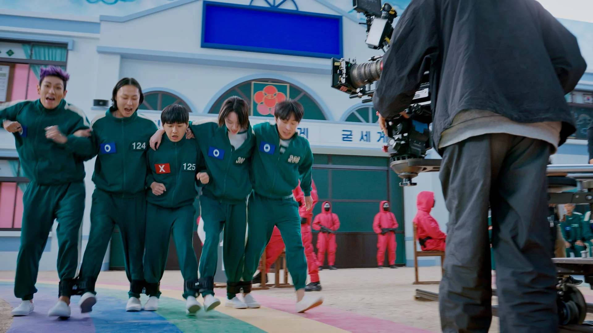 Inside Squid Game S2 — players walking arm in arm between takes with crew and guards
